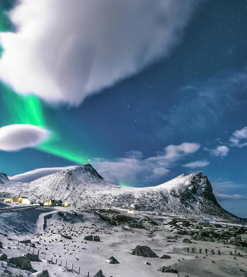Snowy mountains under the aurora borealis in Myrland, Nordland, Norway, showcasing a serene winter night.